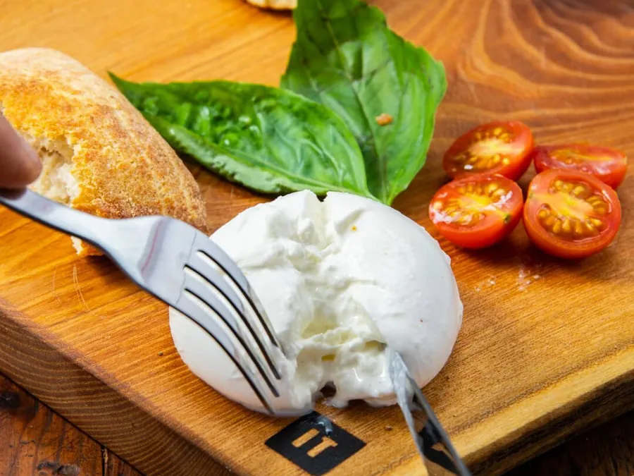 Burrata, tomates cerises et basilic sur une planche en bois