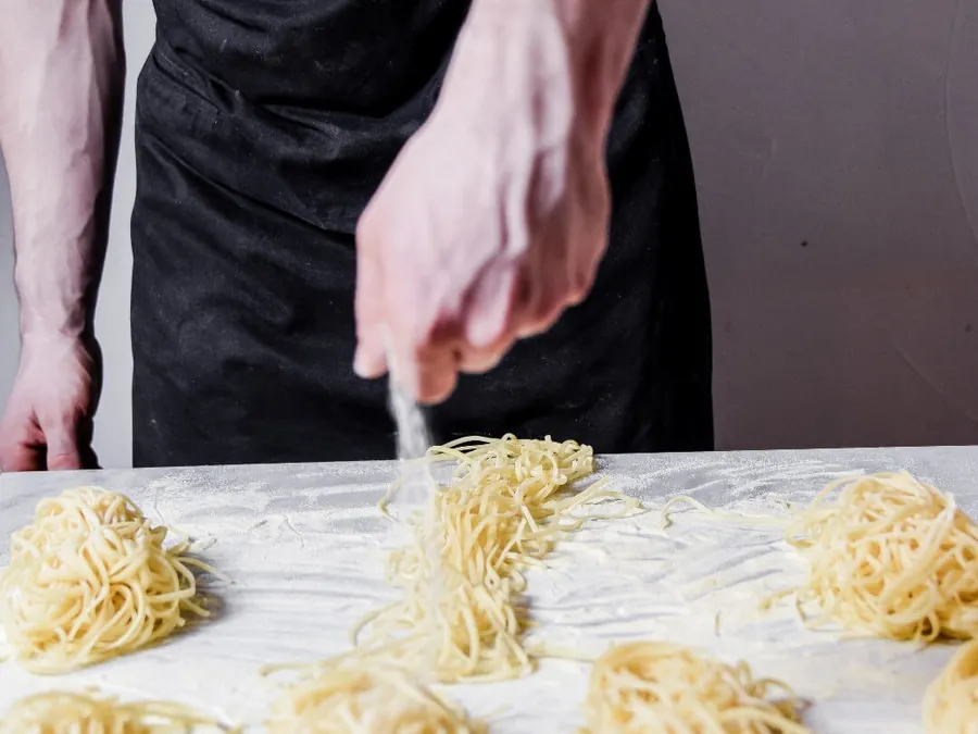 Nids de tagliatelles fraîches façonnés à la main sur le plan de travail fariné
