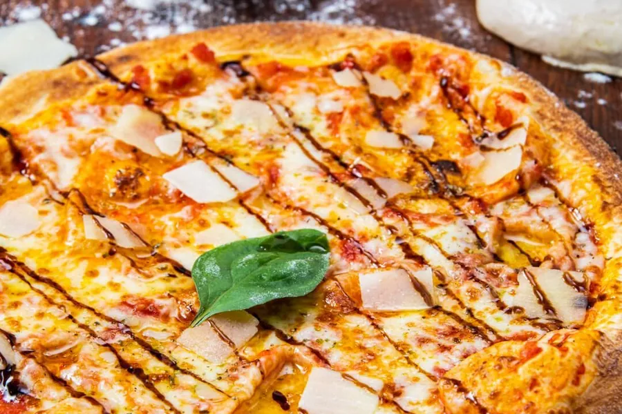 Pizza sortie du four, copeaux de parmesan et basilic